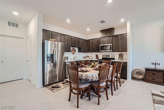 kitchen featuring light tile patterned floors, sink, dark brown cabinetry, and stainless steel appliances