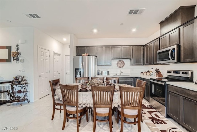 kitchen with sink, dark brown cabinets, light tile patterned flooring, and stainless steel appliances