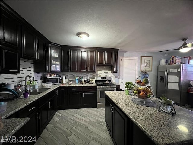 kitchen featuring appliances with stainless steel finishes, sink, decorative backsplash, light stone counters, and light wood-type flooring