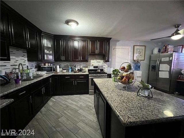 kitchen with a center island, light hardwood / wood-style flooring, stainless steel appliances, light stone countertops, and decorative backsplash