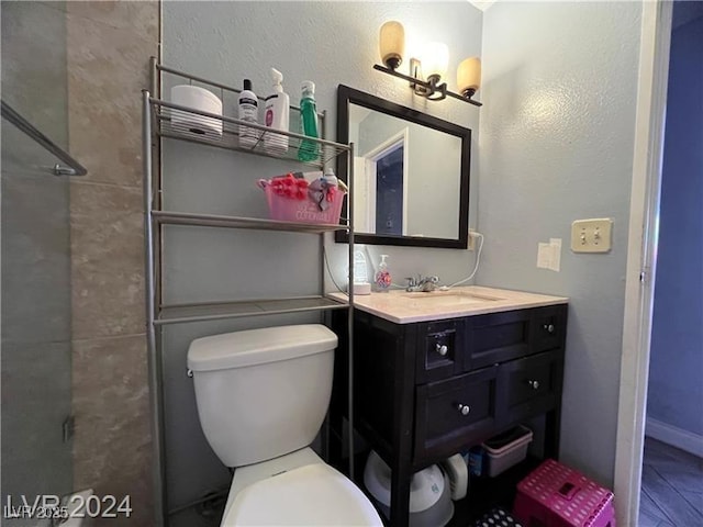 bathroom featuring vanity, a shower with shower door, and toilet