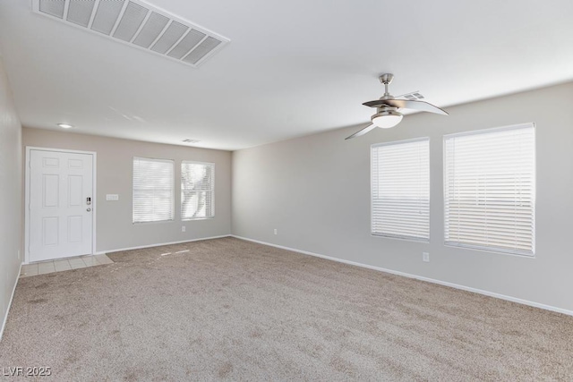 carpeted empty room featuring visible vents, a ceiling fan, and baseboards