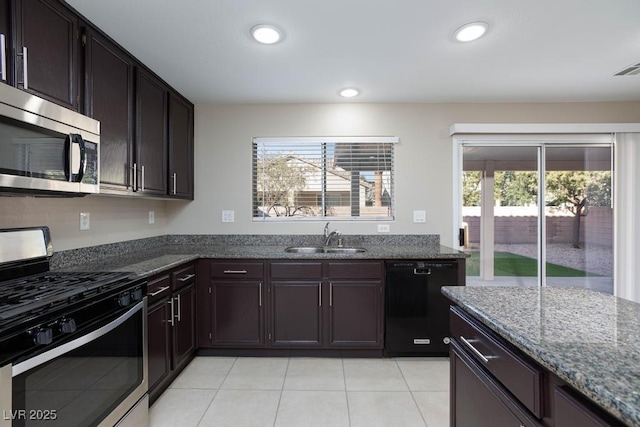 kitchen featuring recessed lighting, stainless steel appliances, dark stone countertops, a sink, and light tile patterned flooring