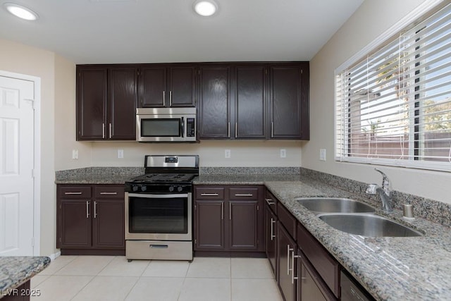 kitchen with light stone countertops, stainless steel appliances, a sink, and light tile patterned floors