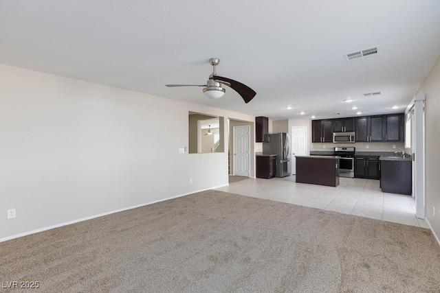 unfurnished living room featuring light carpet, visible vents, baseboards, a ceiling fan, and light tile patterned floors