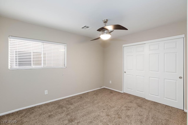 unfurnished bedroom featuring visible vents, a closet, baseboards, carpet flooring, and ceiling fan