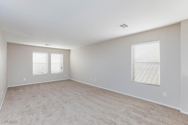 carpeted spare room with visible vents and baseboards