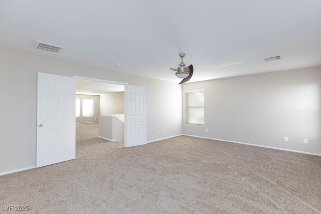 spare room featuring carpet floors, visible vents, and baseboards