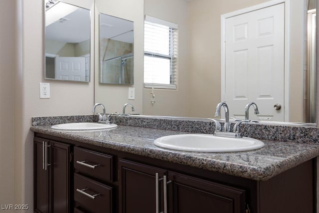 bathroom with a shower with door, a sink, and double vanity
