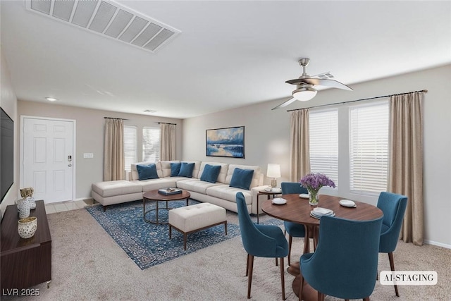 living room with baseboards, visible vents, light colored carpet, and ceiling fan