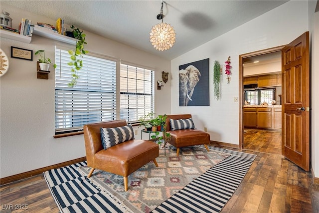 living area with dark hardwood / wood-style flooring, a notable chandelier, and vaulted ceiling