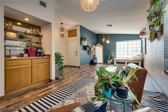 living room with dark wood-type flooring, a textured ceiling, vaulted ceiling, and a notable chandelier