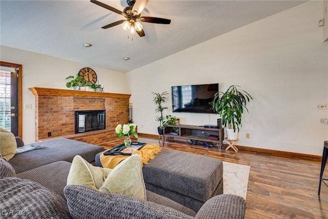 living room with vaulted ceiling, ceiling fan, a fireplace, and wood-type flooring