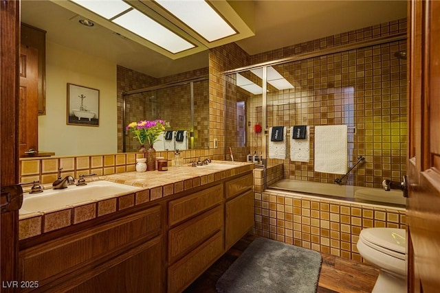 full bathroom featuring shower / bath combination with glass door, tile walls, and toilet