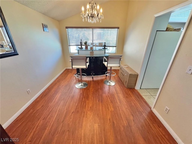 interior space featuring a textured ceiling, light hardwood / wood-style flooring, a notable chandelier, and lofted ceiling