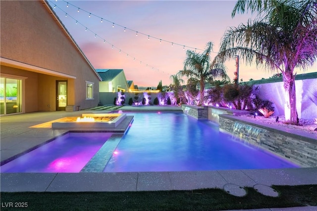 pool at dusk with an in ground hot tub and a patio area