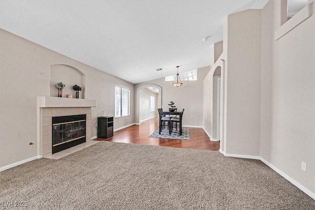 unfurnished living room featuring carpet, a tile fireplace, and vaulted ceiling