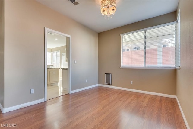 empty room with a chandelier and light hardwood / wood-style flooring