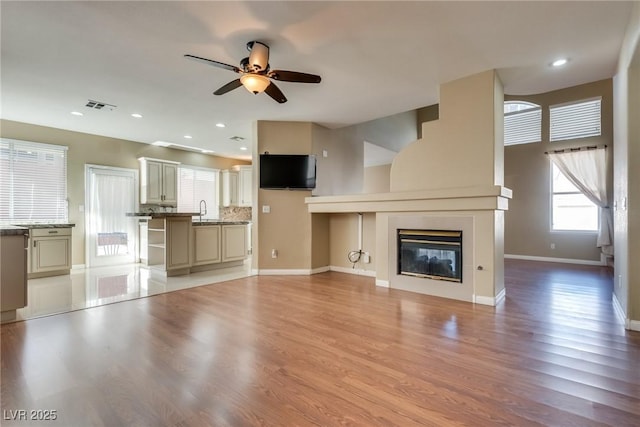 unfurnished living room with sink, light hardwood / wood-style flooring, and ceiling fan