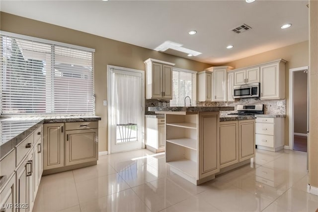 kitchen with appliances with stainless steel finishes, sink, backsplash, cream cabinets, and light tile patterned floors