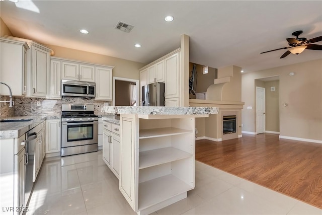 kitchen with a center island, appliances with stainless steel finishes, tasteful backsplash, white cabinets, and sink