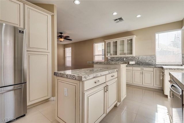 kitchen with a center island, stainless steel appliances, a wealth of natural light, and light tile patterned floors