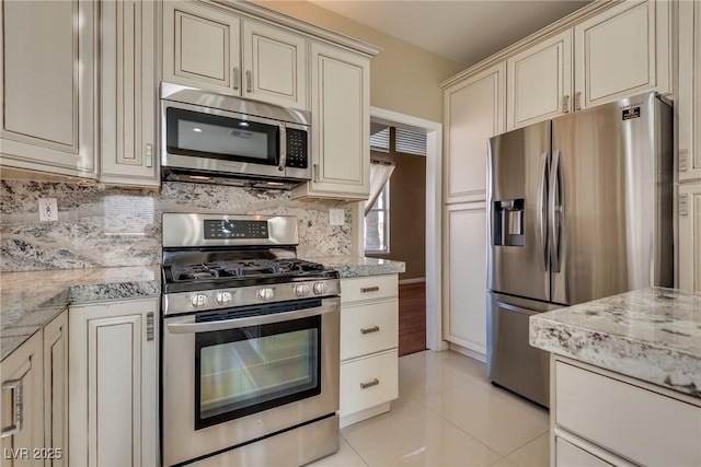 kitchen with light stone counters, cream cabinetry, tasteful backsplash, and stainless steel appliances