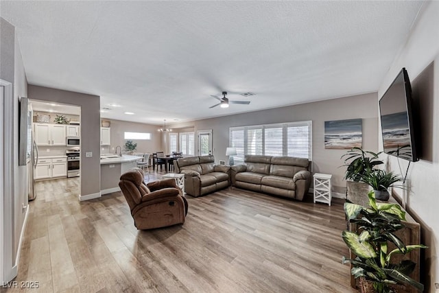 living room with light wood-type flooring, a textured ceiling, and sink