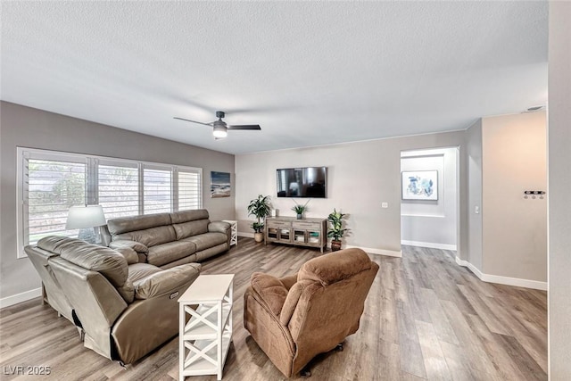 living room with light hardwood / wood-style floors, a textured ceiling, and ceiling fan