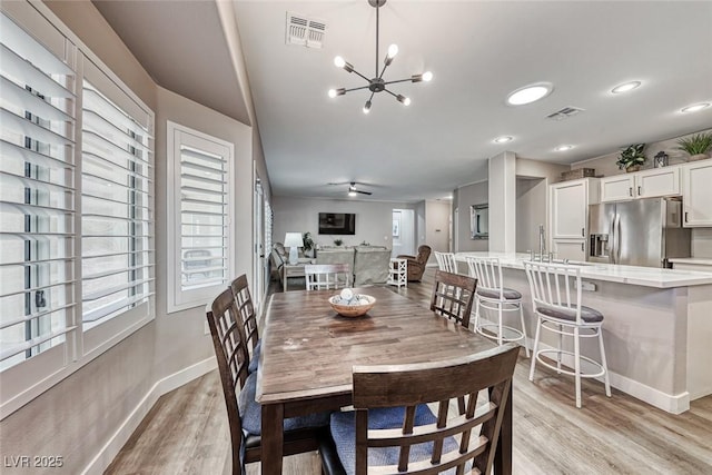 dining area with sink, ceiling fan with notable chandelier, plenty of natural light, and light hardwood / wood-style flooring