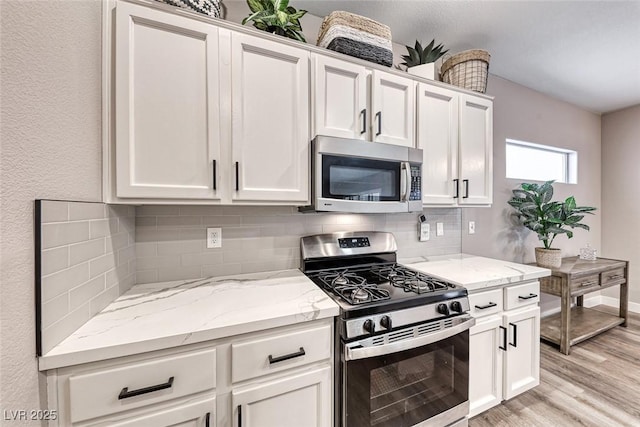 kitchen featuring light stone counters, white cabinetry, and appliances with stainless steel finishes