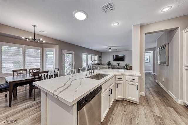 kitchen featuring light stone countertops, dishwasher, sink, white cabinets, and kitchen peninsula