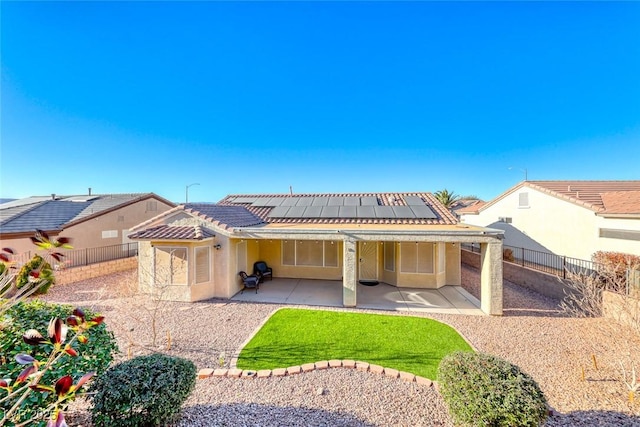 rear view of property featuring a patio area and solar panels