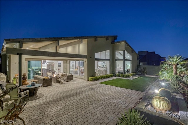 back house at twilight featuring a patio area and an outdoor hangout area