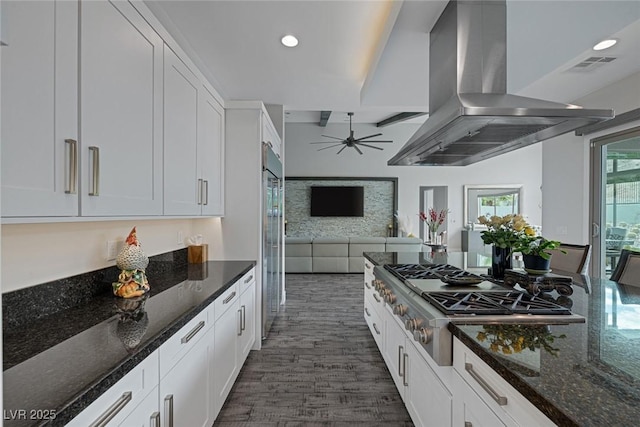 kitchen featuring white cabinets, island range hood, dark stone counters, and appliances with stainless steel finishes