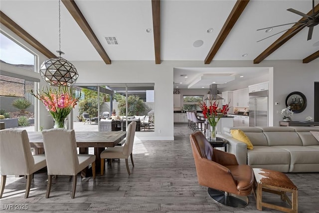 dining room featuring lofted ceiling with beams, ceiling fan with notable chandelier, a wealth of natural light, and dark hardwood / wood-style flooring