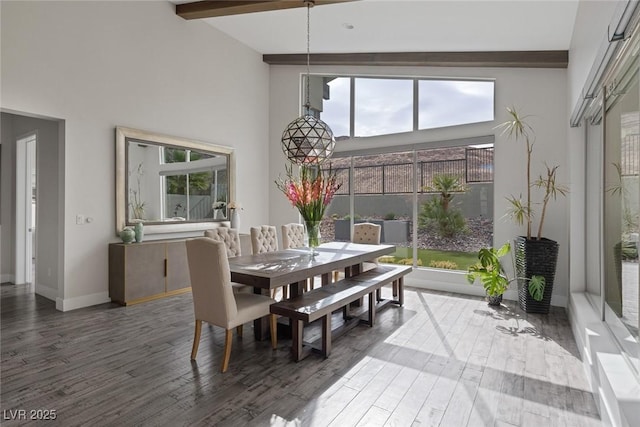 dining area with hardwood / wood-style flooring, beamed ceiling, and a high ceiling