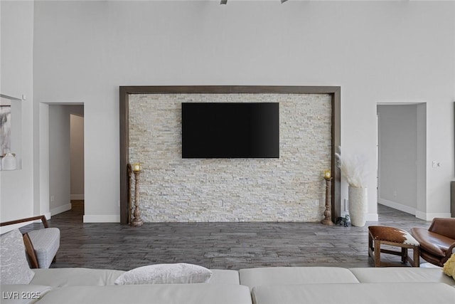 living room with a towering ceiling and dark hardwood / wood-style flooring