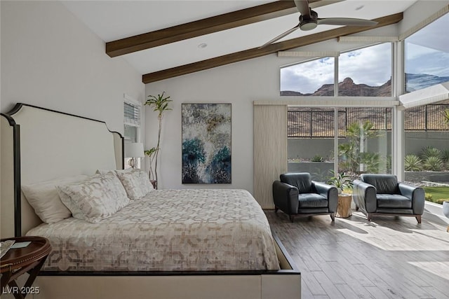 bedroom with ceiling fan, wood-type flooring, multiple windows, and lofted ceiling with beams