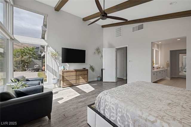 bedroom with ceiling fan, connected bathroom, and beam ceiling