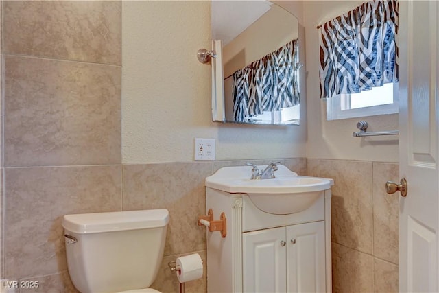 bathroom featuring vanity, tile walls, and toilet