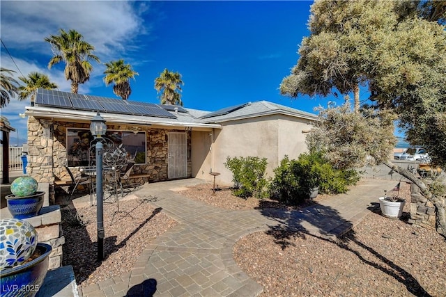 view of front of house with a patio and solar panels