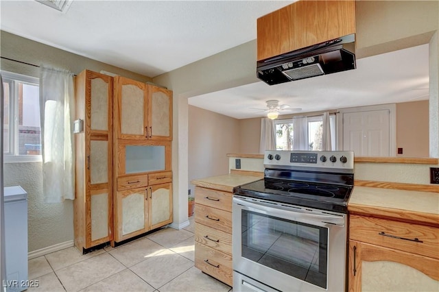 kitchen featuring ceiling fan, stainless steel electric range oven, range hood, and light tile patterned floors