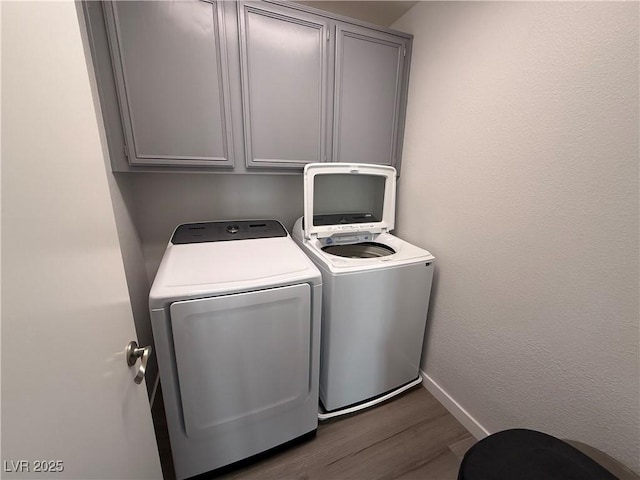 washroom with separate washer and dryer, cabinets, and dark hardwood / wood-style flooring