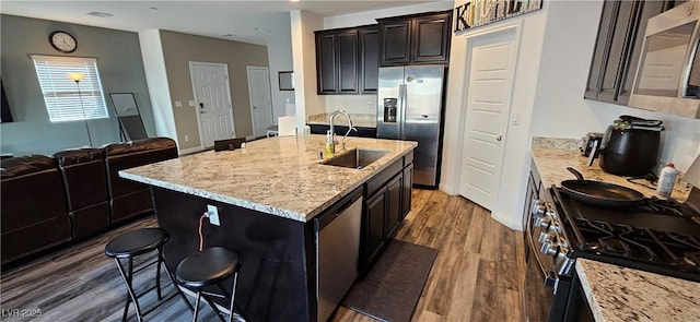 7050 Fossil Rim St, Las Vegas, NV 89084 - kitchen with stainless steel appliances, a sink, dark wood finished floors, light stone counters, and open floor plan