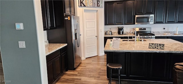 7050 Fossil Rim St, Las Vegas, NV 89084 - kitchen with stainless steel appliances, light wood-type flooring, dark cabinetry, and a breakfast bar