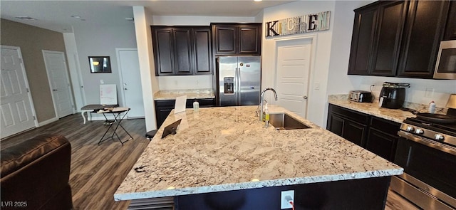 7050 Fossil Rim St, Las Vegas, NV 89084 - kitchen with appliances with stainless steel finishes, a sink, light stone counters, dark wood-type flooring, and a kitchen island with sink