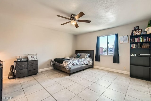 bedroom with a textured ceiling, light tile patterned floors, and ceiling fan