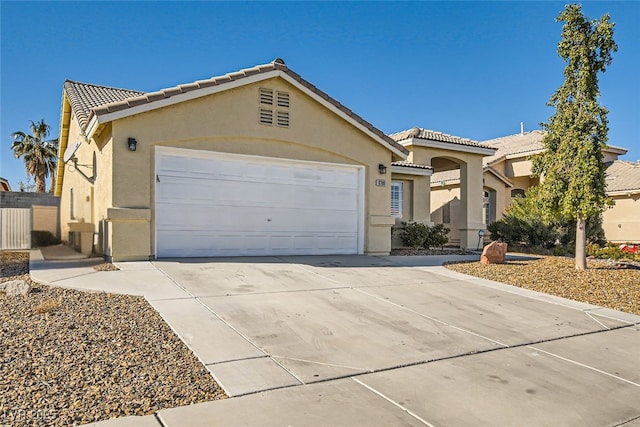 view of front of house featuring a tile roof, stucco siding, concrete driveway, and a garage