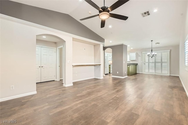 unfurnished living room featuring visible vents, baseboards, vaulted ceiling, wood finished floors, and arched walkways